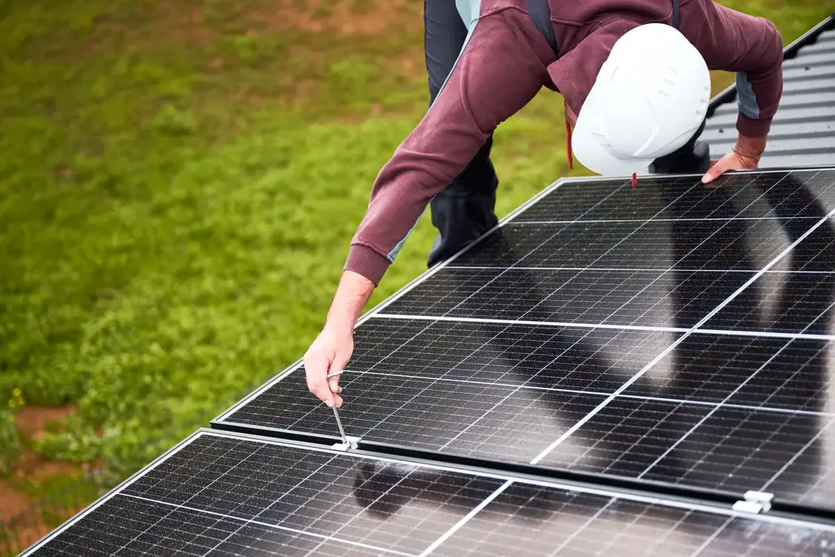 Subvenciones para placas solares en Elche: instalador ajustando un panel sobre una cubierta metálica