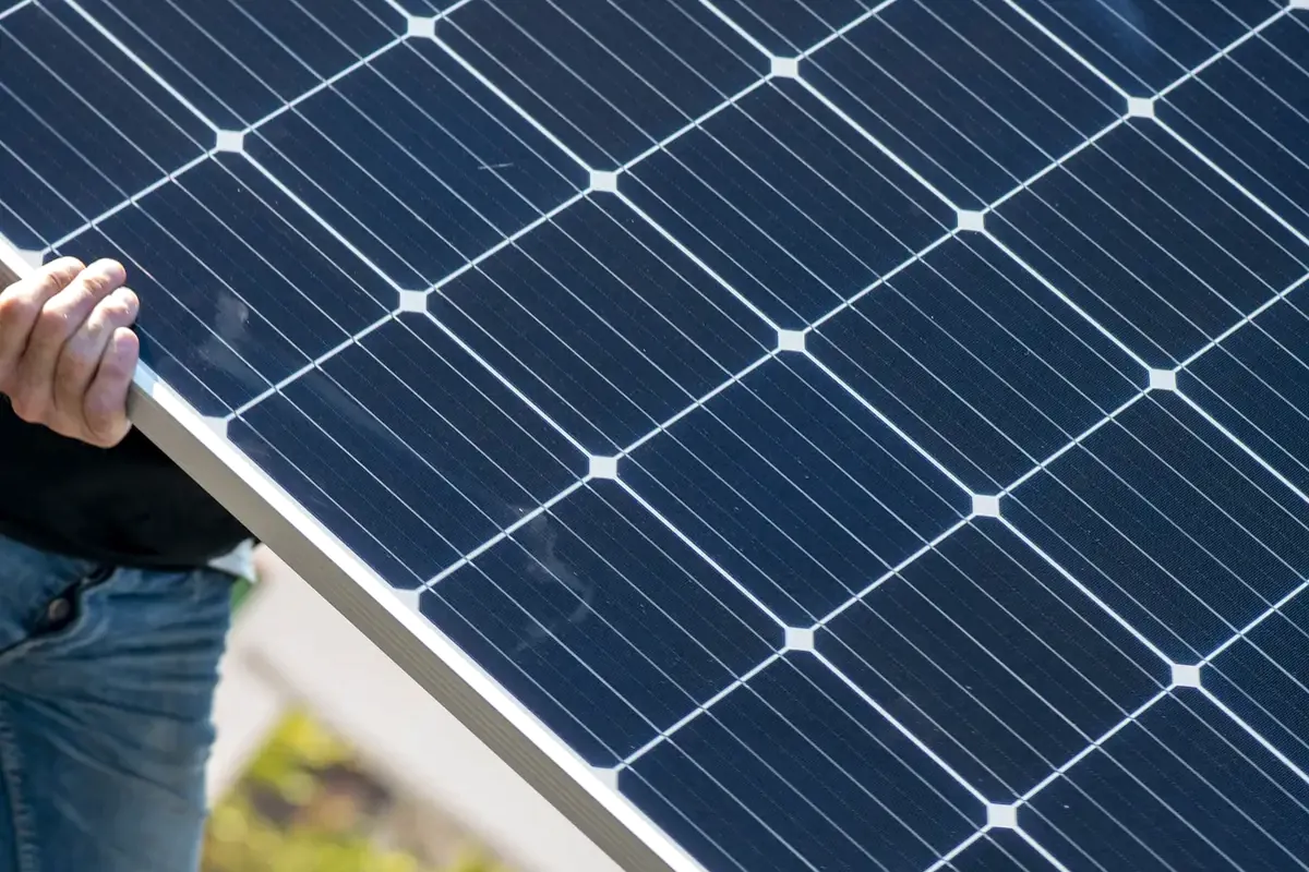 Subvenciones para placas solares en Elche: técnico sosteniendo un panel fotovoltaico